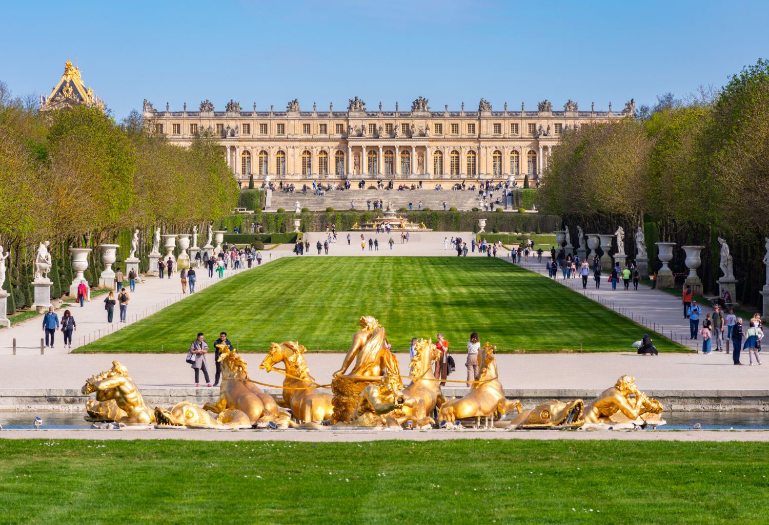 Apollo-fontenen foran Versailles-palasset, med den historiske bygningen som danner en monumental bakgrunn.